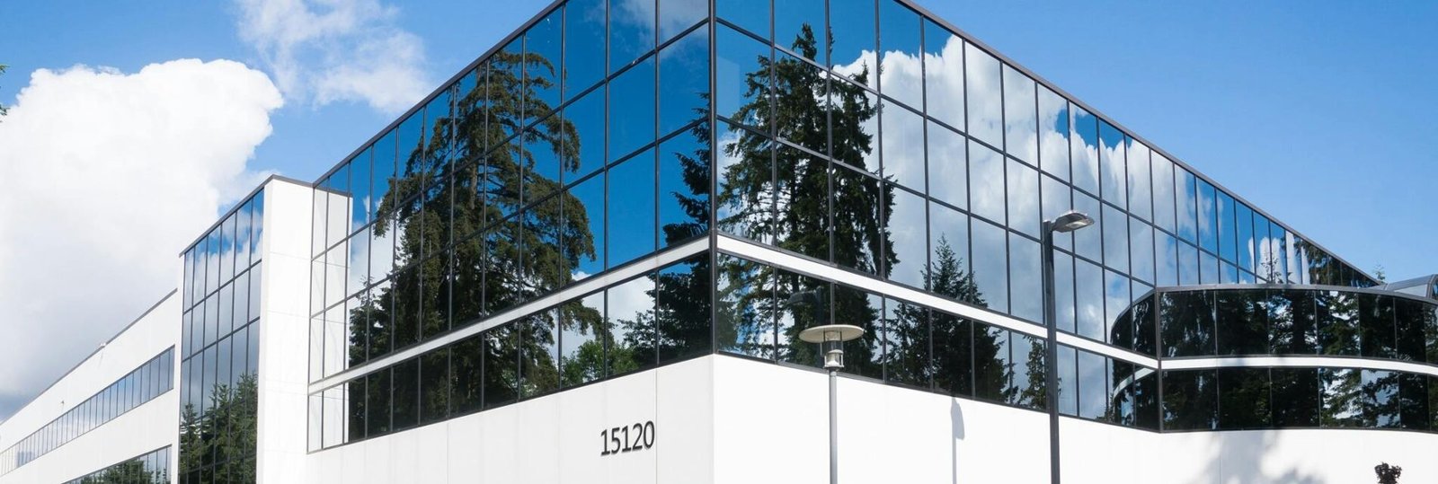 Contemporary office building in Redmond with reflective glass and lush greenery, captured on a sunny day.
